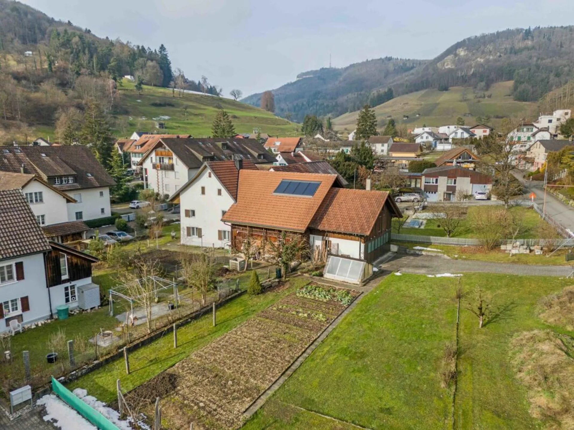 Terrain à bâtir de plus de 1'758 m² avec une maison à deux familles et un grand potentiel de développement dans le centre villageois calme de Remigen